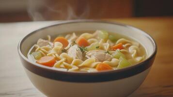 Warm chicken noodle soup in a bowl with carrots, celery, and herbs on a wooden table during a cozy evening photo