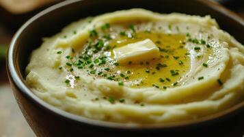 Creamy mashed potatoes topped with butter and chives in a wooden bowl on a rustic table photo