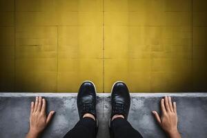 Black shoed feet at platforms edge, hands on either side photo