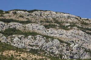 Mountain landscape with blue sky and trees. A church stands on top of the mountain. View from above. Horizontal photo