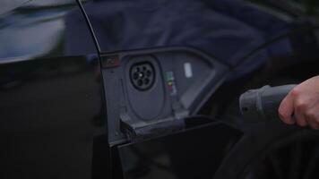A stylish man elegantly dressed is Charching Electric Car on Pulic Charching Station Using A Cable Connection video