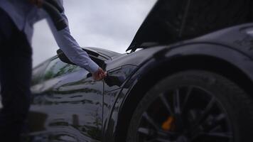 Closeup view of a man Charching Electric Car on Public Charching Station Using A Cable Connection video