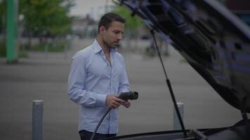 A person charging an electric vehicle at a dedicated station designed for that purpose video