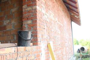 Building under construction. The process of building a brick building. Black bucket in the window opening photo