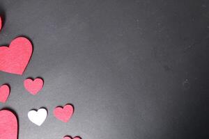Background for Valentine's Day holiday eighth of March. Red and pink hearts on black background top view with space for copy space text photo