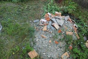 Discarded bricks and concrete on the grass. The problem of disposal of construction waste and residues of building materials photo