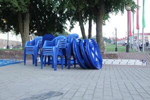 Blue plastic chairs stand in a heap in a group. Recycled plastic furniture photo