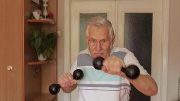 Senior elderly caucasian man doing sports exercises with dumbbells at home video