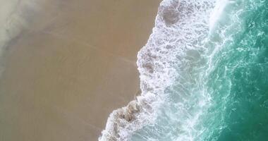 aerial drone ascending and turning over the waves arriving at the shore of a beach video