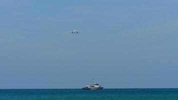 An airplane approaches over the ocean while a military vessel is traveling on the surface of the water video