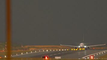 Airplane with an unrecognizable livery speed up before takeoff, view through the airport fence. Flight departure. Plane on the runway. Glowing runway video
