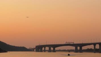 Airplane flies high over the city bridge at sunset, long shot. The Hong Kong Macau Bridge is a megastructure spanning the sea and linking Hong Kong, Zhuhai and Macau video