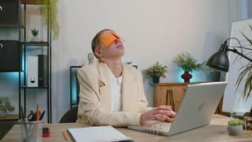 Inefficient tired lazy businesswoman working sleeping on laptop computer with eyes stickers on face video