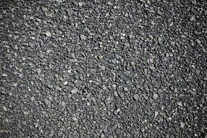 A rugged and dark asphalt texture background with a slightly rough surface photo