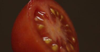 Rotate of the halves of fresh ripe cut tomato on a dark background video