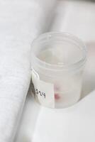 Container with an skin lesion removed from a patient. Dermatologist carrying out a removal of benign skin lesion on the face of a young male patient. photo
