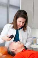 Dermatologist making a routine checkup on a senior male patient using a magnifying glass. photo