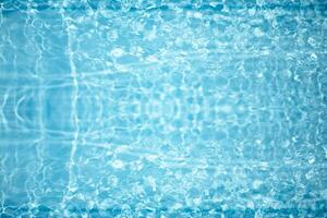 Blue water with ripples on the surface. Defocus blurred transparent blue colored clear calm water surface texture with splashes and bubbles. Water waves with shining pattern texture background. photo