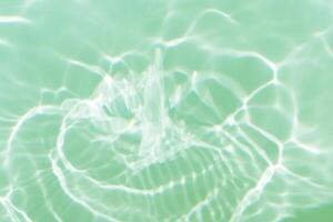 Bluewater waves on the surface ripples blurred. Defocus blurred transparent blue colored clear calm water surface texture with splash and bubbles. Water waves with shining pattern texture background. photo