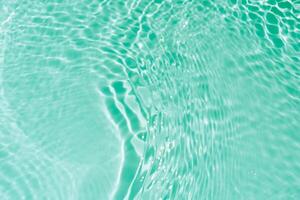 Bluewater waves on the surface ripples blurred. Defocus blurred transparent blue colored clear calm water surface texture with splash and bubbles. Water waves with shining pattern texture background. photo