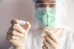 Scientist doctor hand holding syringe with a sample test bottle of Covid-19 vaccine. photo