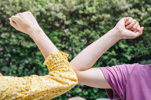 Cropped shot of two women bump elbows for greeting during coronavirus epidemic. The elbow bump was suggested as an alternative way for reduce your risk of spreading or contracting the virus. photo