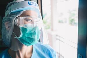 Nurse having tired from work while wearing PPE suit for protect coronavirus disease. photo