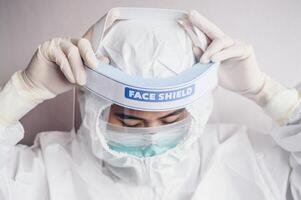 Healthcare worker trying to wearing PPE suit for working in hospital during Covid-19 pandemic. PPE is equipment that will protect the user against health or safety risks at work. photo