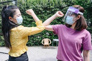 Two woman bump elbows for greeting during coronavirus epidemic. The elbow bump was suggested as an alternative way for reduce your risk of spreading or contracting the virus. photo