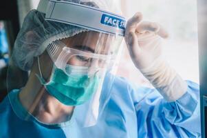 Nurse having headache and tired from work while wearing PPE suit for protect coronavirus disease. photo