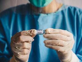 Close up of scientist doctor hand holding a sample test bottle of Covid-19 vaccine. photo
