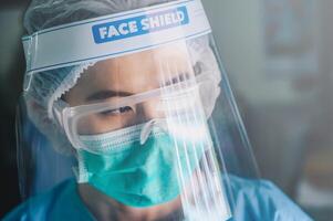 Nurse having tired from work while wearing PPE suit for protect coronavirus disease. PPE while protecting healthcare workers from exposure to the COVID-19 virus in healthcare settings. photo