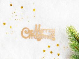 Flat lay frame various green and gold christmas decor and Wish you Merry Christmas on artificial snow background. photo