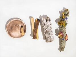 Items for spiritual cleansing - sage and aromatic herbs bundle and palo santo incense sticks on white background photo
