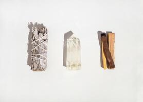 Items for spiritual cleansing - sage bundle, palo santo incense sticks and quartz crystal on white background photo