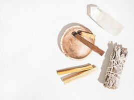 Items for spiritual cleansing - sage bundle, palo santo incense sticks and quartz crystal on white background. photo