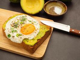 Toast with avocado and eggs served on a wooden cutting board. Top view. Space for text photo
