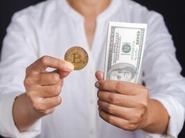 Businessman holding a bitcoin coin and US banknote in his hand. Bitcoin is a symbol of cryptocurrency, electronic virtual money. Blockchain technology, payment, and digital asset concept photo