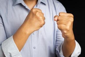 Hand of businessman raised fist air with a black background. Space for text. Concept of victory, success, and winning photo