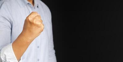 Hand of businessman raised fist air with a black background. Space for text. Concept of victory, success, and winning photo