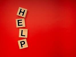 HELP word is written on wood blocks isolated on a red background. Top view. Close-up photo