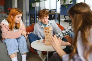 The company of young people plays a table game called jenga photo
