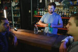 Attractive bartender is smiling and taking order of two men sitting at bar counter in pub photo