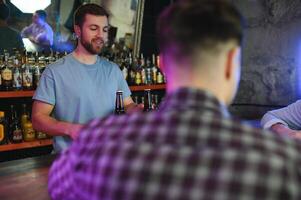 Handsome bar tender standing behind his counter in a pub photo