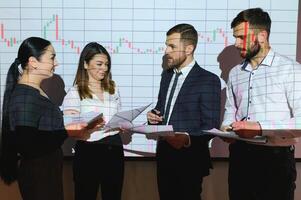 Group of business people working at modern office.Technical price graph, red and blue candlestick chart and stock trading computer screen background. Double exposure. Traders analyzing data photo