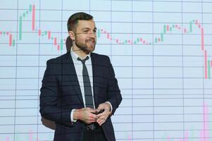 Man is standing near projector and showing graphs and business graphs. photo