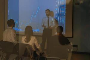 Man is standing near projector and showing graphs and business graphs. photo