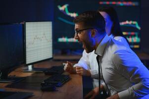 Team of stockbrokers are having a conversation in a dark office with display screens photo