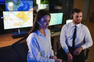 Center of dispatching maintenance. Portrait of cheerful woman and man working via headset microphone while sitting on navigation controller board photo