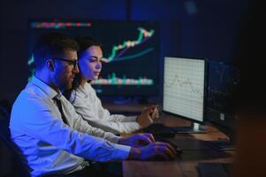 Team of traders working at monitor computer and browsing online in trading office photo